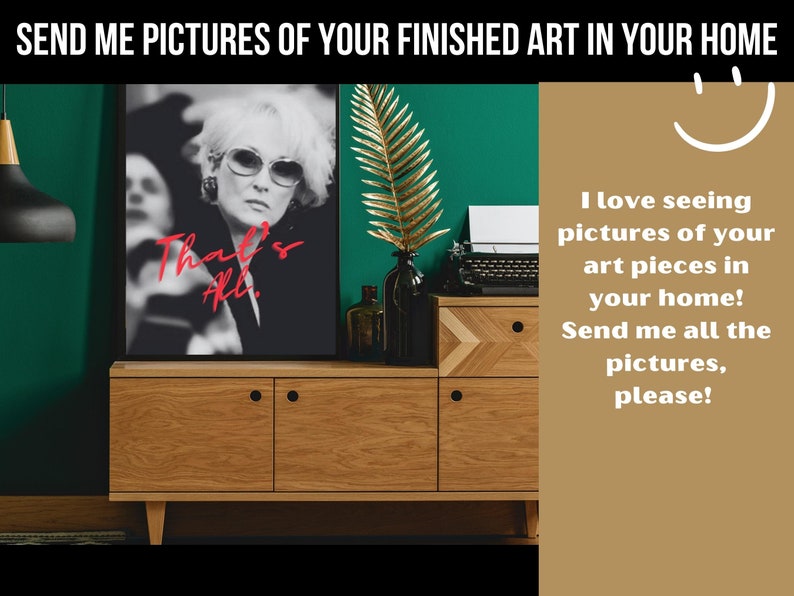 May include: A wooden dresser with two drawers and a black framed print of a woman with the text "That's All." The dresser is in front of a green wall with a gold leaf plant.