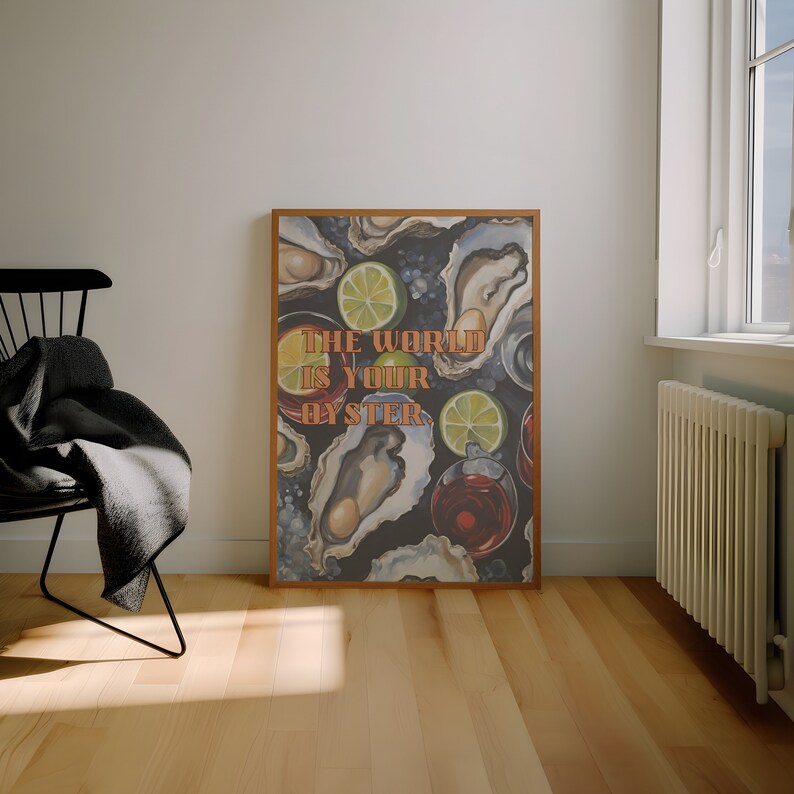 May include: A framed art print featuring a dark background with illustrations of oysters, lime slices, and glasses of red liquid. The text "THE WORLD IS YOUR OYSTER" is in orange letters. The print is displayed in a room with a chair and a window.
