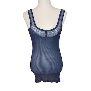 May include: A blue tank top with a lace trim and a button closure. The tank top is made of a waffle knit fabric.