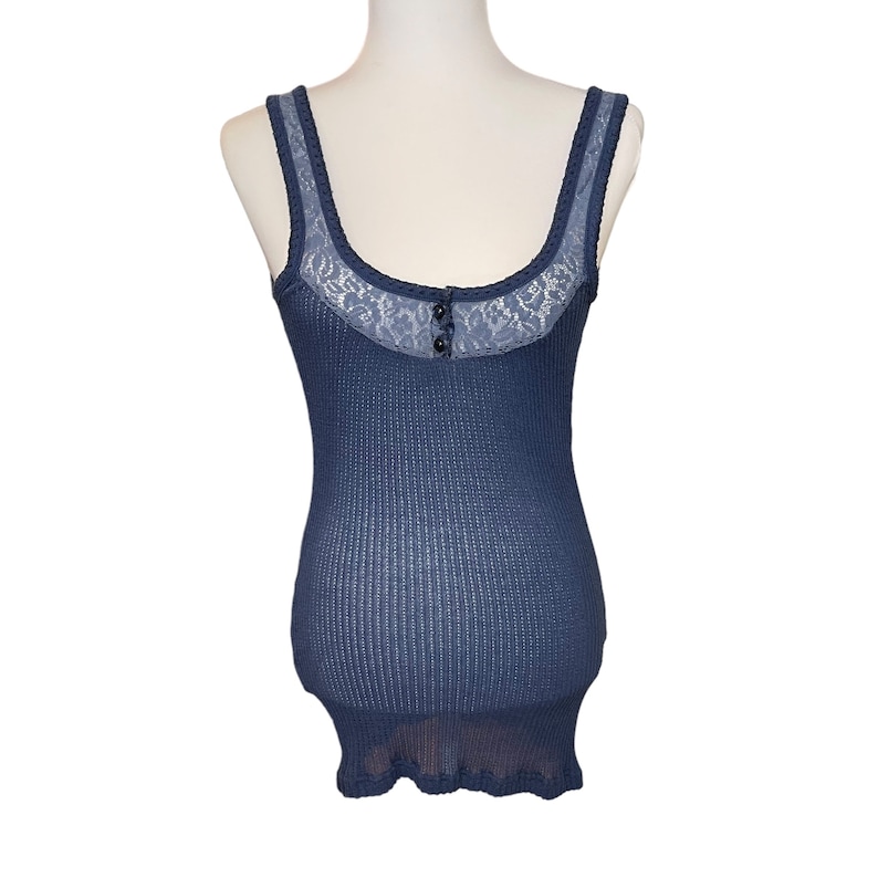 May include: A blue tank top with a lace trim and a button closure. The tank top is made of a waffle knit fabric.