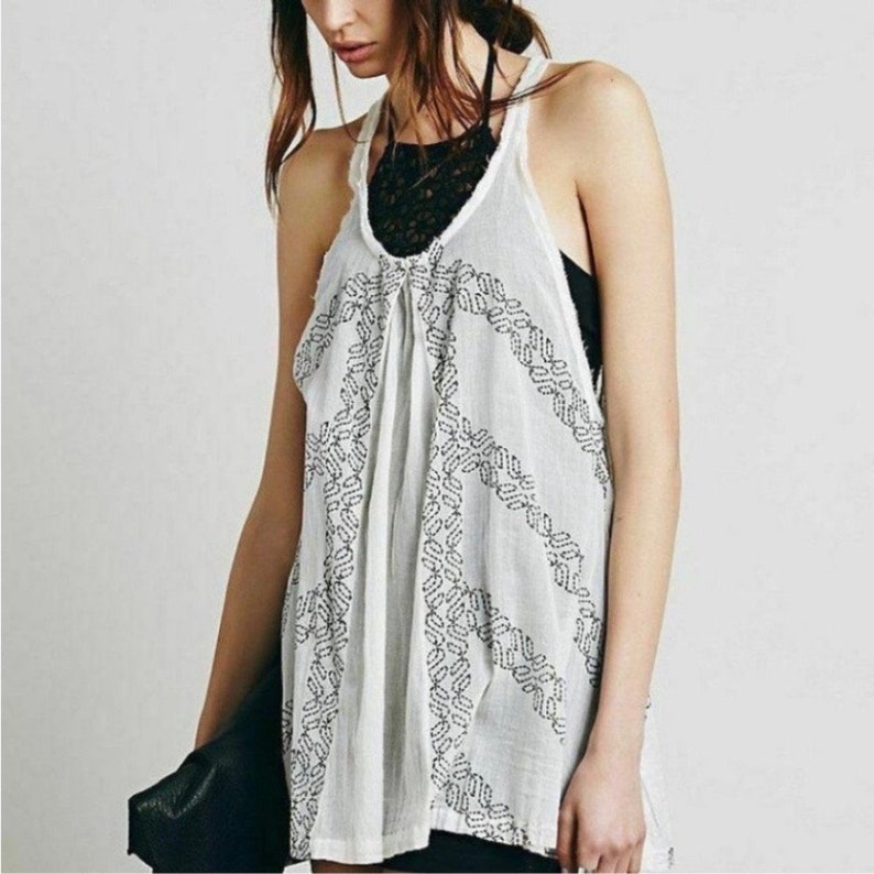 May include: White sleeveless top with a black peace sign design. The top is made of a lightweight fabric and has a relaxed fit.