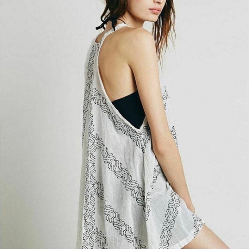 May include: White sleeveless tunic with a geometric pattern in black. The tunic has a loose fit and a scoop neck.