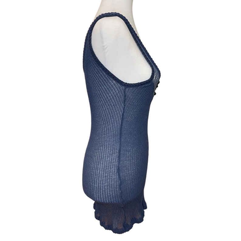 May include: A navy blue tank top with a lace trim and a ruffled hem. The tank top is made of a lightweight, breathable fabric.