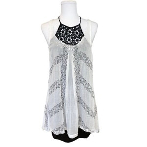 May include: White sleeveless top with a black crochet neckline and a peace sign pattern.