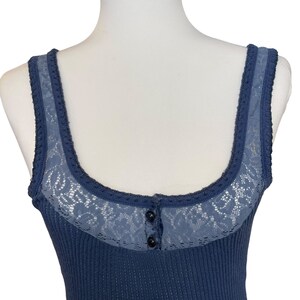 May include: A blue ribbed tank top with a lace trim and a single button closure at the neckline.