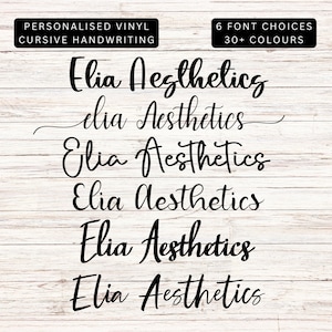 May include: Six different font styles of the name "Elia Aesthetics" written in cursive handwriting. The text is black and is displayed on a white wood background.