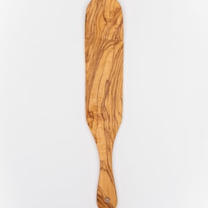 May include: A wooden spatula with a long, narrow blade and a rounded handle. The spatula is made of olive wood and has a natural wood grain.