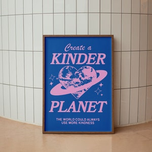 May include: A blue poster with the text "Create a Kinder Planet" in pink lettering. The poster features a pink heart-shaped planet with a ring around it. The text "The world could always use more kindness" is also included in pink lettering.