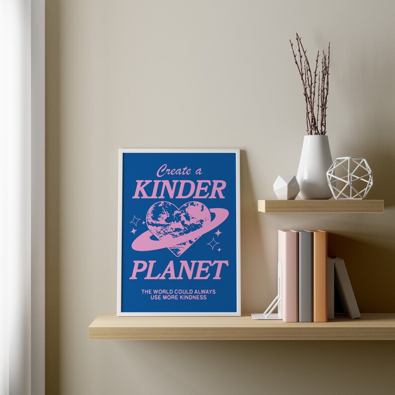 May include: A blue and pink poster with the text "Create a Kinder Planet" and a pink heart-shaped planet with a ring around it. The text below the planet reads "The world could always use more kindness."