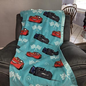 Cars Lightning McQueen and Jackson Storm, Kids Fleece Blanket with a light shimmering teal satin trim