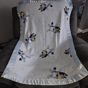 Bluey, Infant Receiving Fleece Blanket with a matching light blue satin trim.