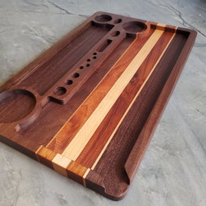 Könnte beinhalten: Ein Holz-Rolltablett mit einem mehrfarbigen Streifenmuster. Das Tablett verfügt über einen eingebauten Grinder, eine kleine Schale und eine große Schale.