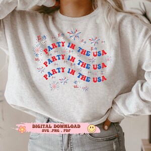 May include: A gray sweatshirt with the text "Party in the USA" repeated three times in a circle. Red, white, and blue firework designs surround the text.