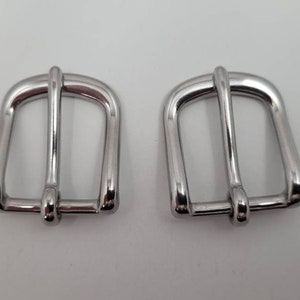 Puede incluir: Dos cierres de hebilla de metal plateado para correas o cinturones.