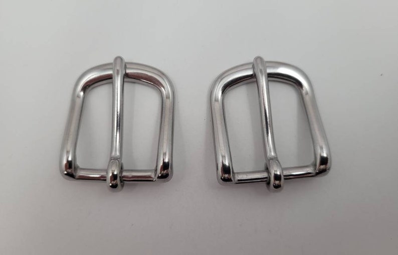 Puede incluir: Dos cierres de hebilla de metal plateado para correas o cinturones.