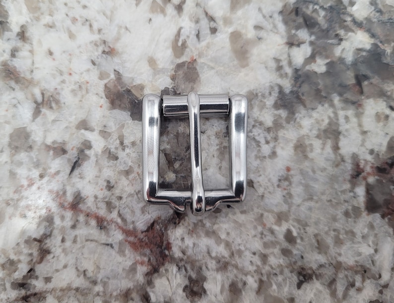 May include: A silver metal buckle for a belt or strap.