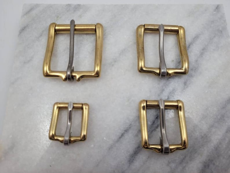 K&ouml;nnte beinhalten: Vier goldfarbene Metall-G&uuml;rtelschnallen mit silberfarbenen Zungen. Die Schnallen sind in verschiedenen Gr&ouml;&szlig;en.