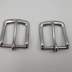 Puede incluir: Dos hebillas de cintur&oacute;n de metal plateado. Las hebillas son rectangulares con un borde redondeado y tienen un acabado liso y pulido.