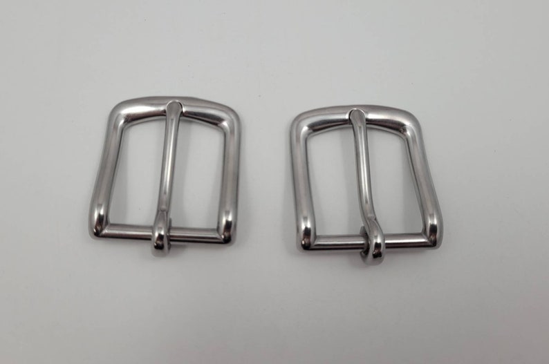 Puede incluir: Dos hebillas de cintur&oacute;n de metal plateado. Las hebillas son rectangulares con un borde redondeado y tienen un acabado liso y pulido.