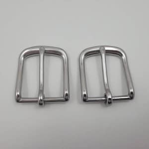 Puede incluir: Dos hebillas de cintur&oacute;n de metal plateado. Las hebillas son rectangulares con un borde redondeado y tienen un acabado liso y pulido.