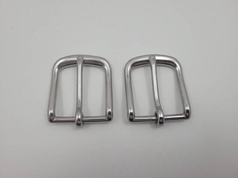 Puede incluir: Dos hebillas de cintur&oacute;n de metal plateado. Las hebillas son rectangulares con un borde redondeado y tienen un acabado liso y pulido.