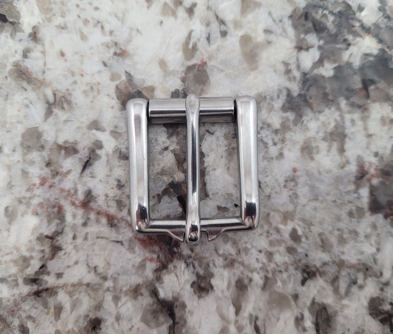 May include: A silver metal buckle for a belt or strap.