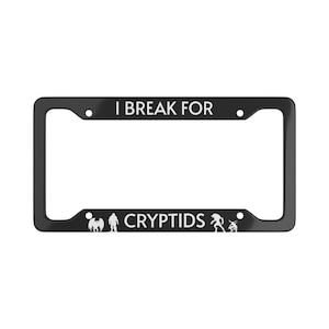 May include: Black license plate frame with white text that reads "I BREAK FOR CRYPTIDS." The frame features illustrations of cryptids, including Bigfoot and an alien. A fun and unique accessory for any vehicle.