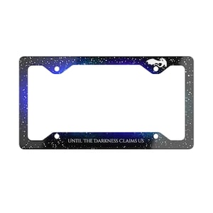 Puede incluir: Marco de matrícula con un diseño de noche estrellada en tonos azules, morados y negros. El marco tiene un emblema blanco y el texto "UNTIL THE DARKNESS CLAIMS US" en blanco.