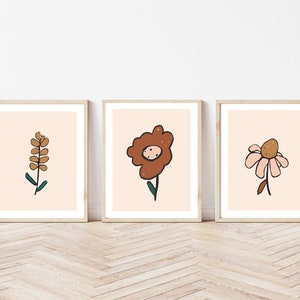 May include: Three framed prints with minimalist illustrations of flowers in brown, pink, and green on a light peach background.