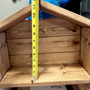 Peut inclure: &Eacute;tag&egrave;re en bois en forme de maison, teinte dans une teinte marron chaud. L'&eacute;tag&egrave;re mesure environ 28 cm de haut. La conception comprend un toit en pente et une ouverture rectangulaire, adapt&eacute;e pour exposer des objets ou comme pi&egrave;ce d&eacute;corative.