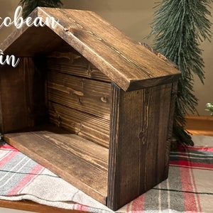 Peut inclure: Une cr&egrave;che en bois avec une finition Jacobean fonc&eacute;e. La structure a un toit en pente et une base rectangulaire. Le texte "Jacobean Stain" est visible. D&eacute;coration de No&euml;l pour une sc&egrave;ne de la Nativit&eacute;.