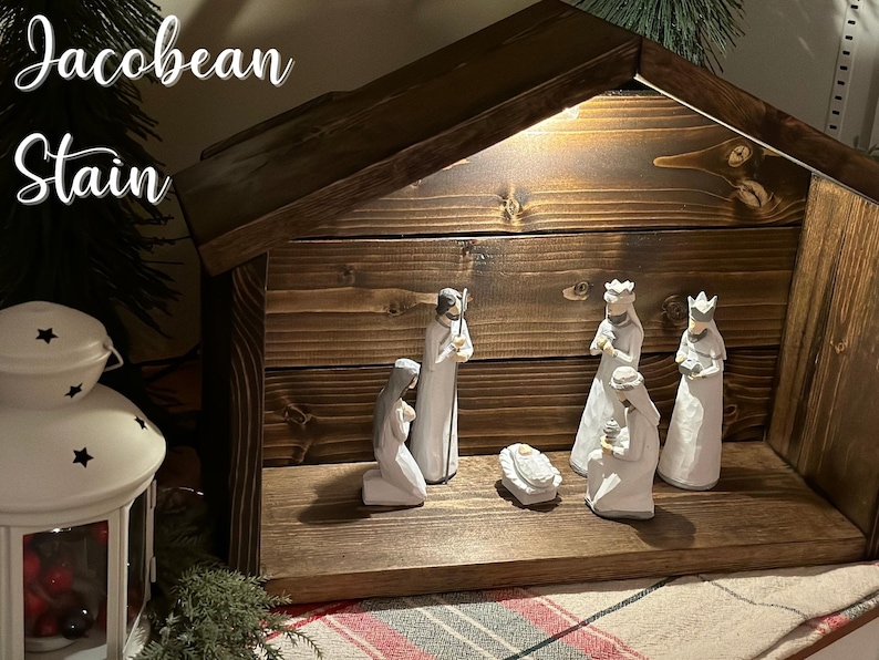 Peut inclure: Une cr&egrave;che en bois avec une teinture fonc&eacute;e. La sc&egrave;ne comprend des figurines de Marie, Joseph, des trois rois mages et de l'enfant J&eacute;sus dans une mangeoire. Le texte "Jacobean Stain" est visible en haut &agrave; gauche.