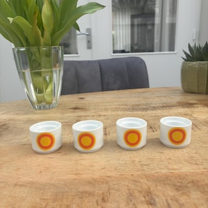 Op de afbeelding: Een witte keramische mok met een zwart handvat en de tekst "But First, Coffee" in een zwarte, vette letter. De mok staat op een wit oppervlak.