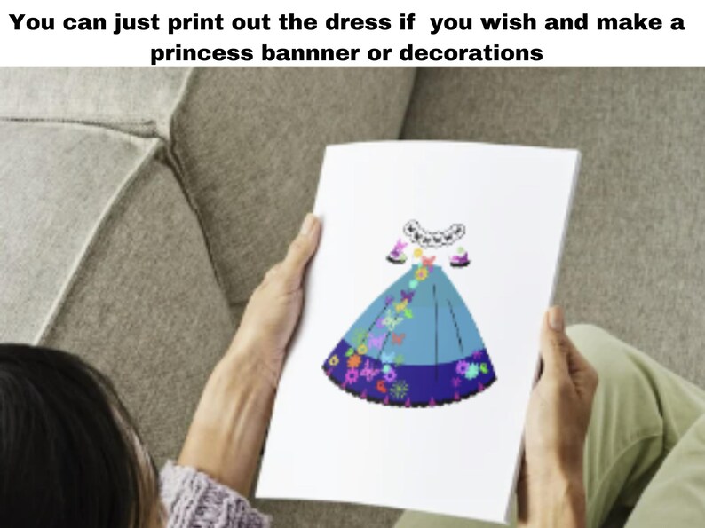 May include: A printable paper craft of a blue princess dress with colorful floral and butterfly designs. The dress is shown on a white sheet of paper held by a person's hands.