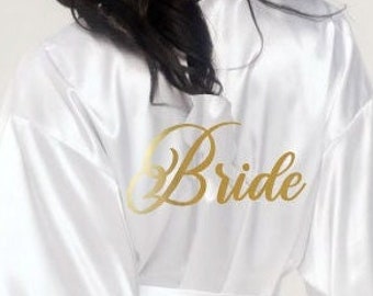 Op de afbeelding: Witte satijnen badjas met gouden opschrift "Bride" op de rug.