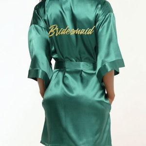 May include: A dark green satin robe with the word 'bridesmaid' embroidered in gold glitter on the back.