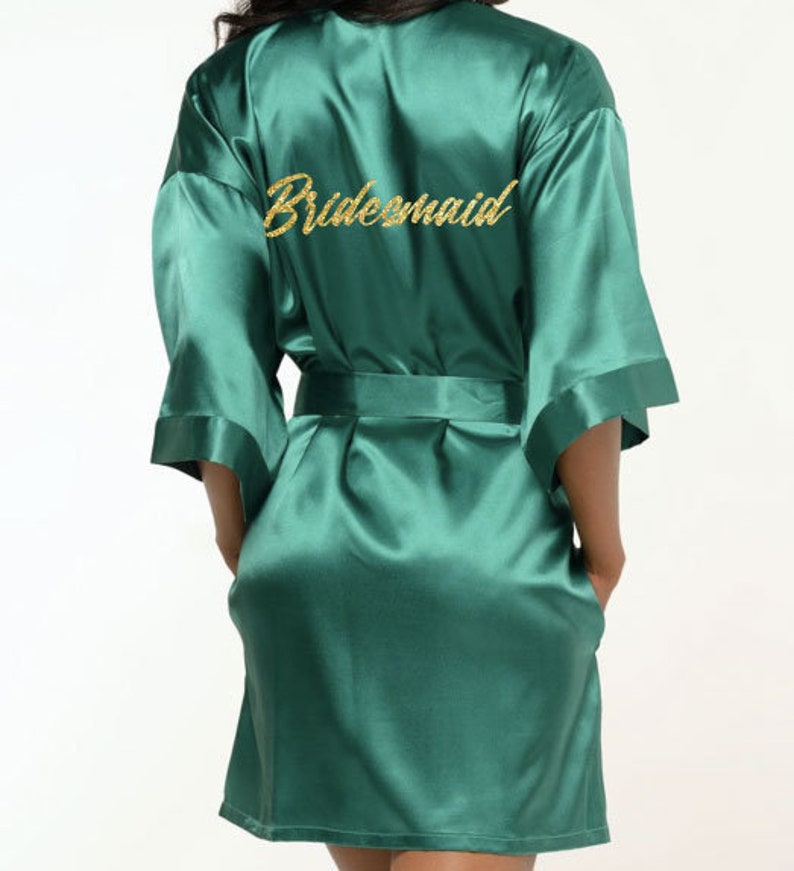 May include: A dark green satin robe with the word 'bridesmaid' embroidered in gold glitter on the back.