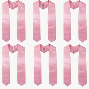 May include: Six light pink graduation stoles. Each stole is made of a smooth, satin-like material and features a V-neck design. The stoles are arranged in a grid pattern, showcasing their identical design and colour.