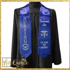 May include: A black graduation gown with a blue nursing sash. The sash has the word "NURSING" vertically embroidered in white, along with a school logo. The other side of the sash has the name "Susanna Lee", the letters "RN", and "CLASS OF 2025".