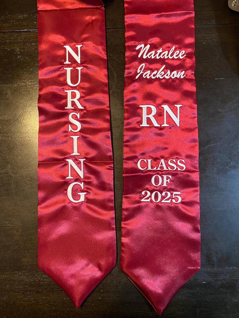 May include: Two maroon graduation stoles. One stole reads "NURSING" in white lettering. The other stole reads "Natalee Jackson", "RN", and "CLASS OF 2025" in white lettering.