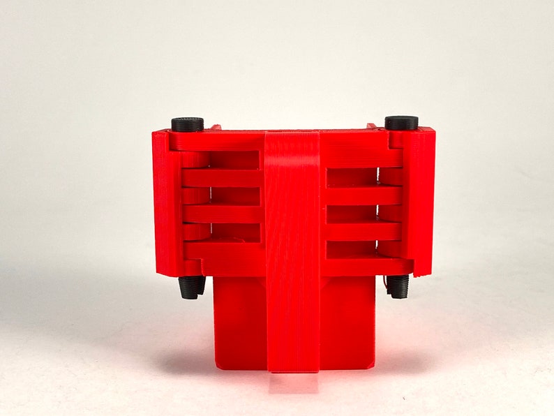 Puede incluir: Un objeto de pl&aacute;stico rojo con una serie de ranuras y botones negros en los lados. El objeto est&aacute; dise&ntilde;ado para contener varios art&iacute;culos.
