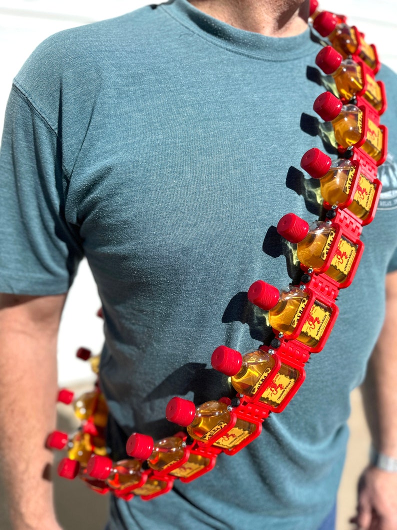 May include: A red and black chain with small bottles of Fireball Cinnamon Whisky attached. The chain is worn around a person's neck.