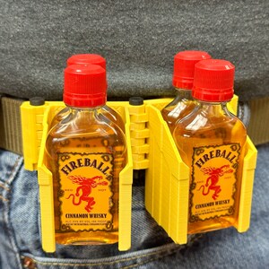 Puede incluir: Porta botellas de pl&aacute;stico amarillo para cuatro botellas peque&ntilde;as de whisky de canela Fireball. El porta botellas est&aacute; sujeto a un cintur&oacute;n marr&oacute;n y se lleva en la cintura.