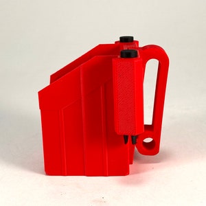 Puede incluir: Un portacargadores de pl&aacute;stico rojo con un clip para cintur&oacute;n. El portacargadores tiene una superficie texturizada y un asa negra.