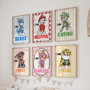 May include: Six framed wall art prints featuring Paw Patrol characters. Each print displays a puppy with a descriptive word: I AM BRAVE in blue, I AM HELPFUL in red, I AM CARING in green, I AM SMART in orange, I AM FEARLESS in pink, and I AM STRONG in yellow.