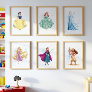 May include: Six framed watercolour prints of Disney princesses. The princesses are Snow White in a yellow dress, Ariel in a green dress, Elsa in a blue dress, Rapunzel in a pink dress, Anna in a blue dress and a purple cape, and Moana in a tan outfit.