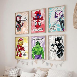May include: Six framed superhero art prints. Each print features a different character with a motivational phrase: "I AM BRAVE", "I AM POLITE", "I AM LOVED", "I AM KIND", "I AM STRONG", and "I AM SMART". The prints have a light wood frame.