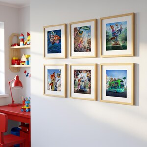 May include: Six framed prints featuring colorful illustrations from the animated movie Zootopia. The prints are in light wood frames and are arranged on a white wall. The images depict various scenes and characters from the film.