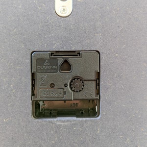 May include: Close-up of a black clock mechanism with the text "DUGENA MADE IN GERMANY" and "IEC  RB +" printed on it.