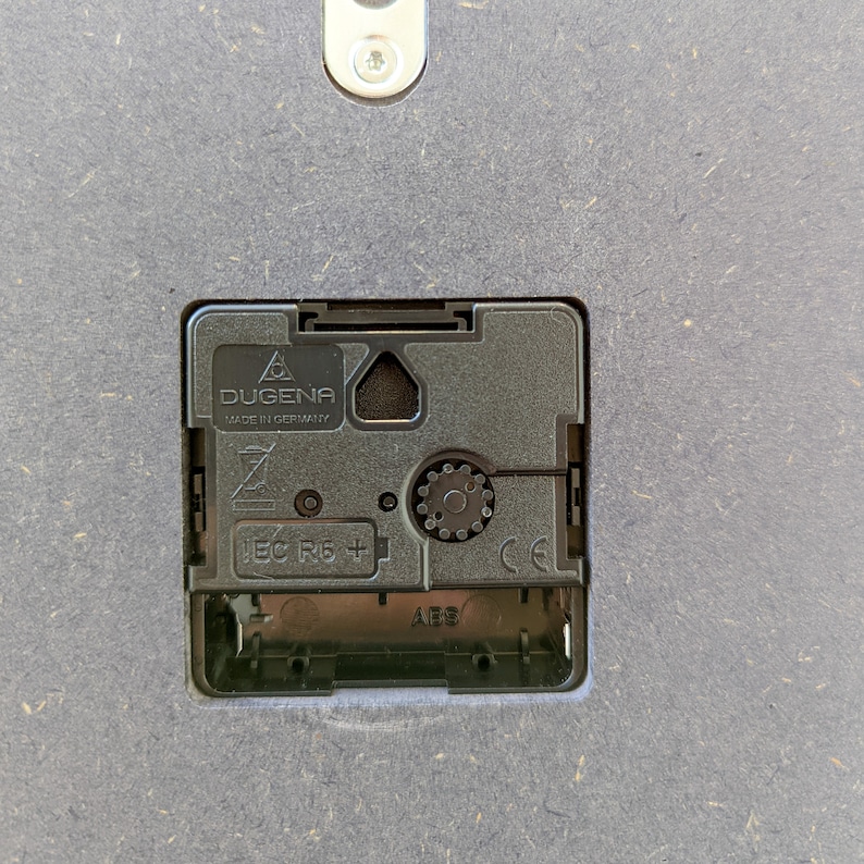 May include: Close-up of a black clock mechanism with the text "DUGENA MADE IN GERMANY" and "IEC  RB +" printed on it.